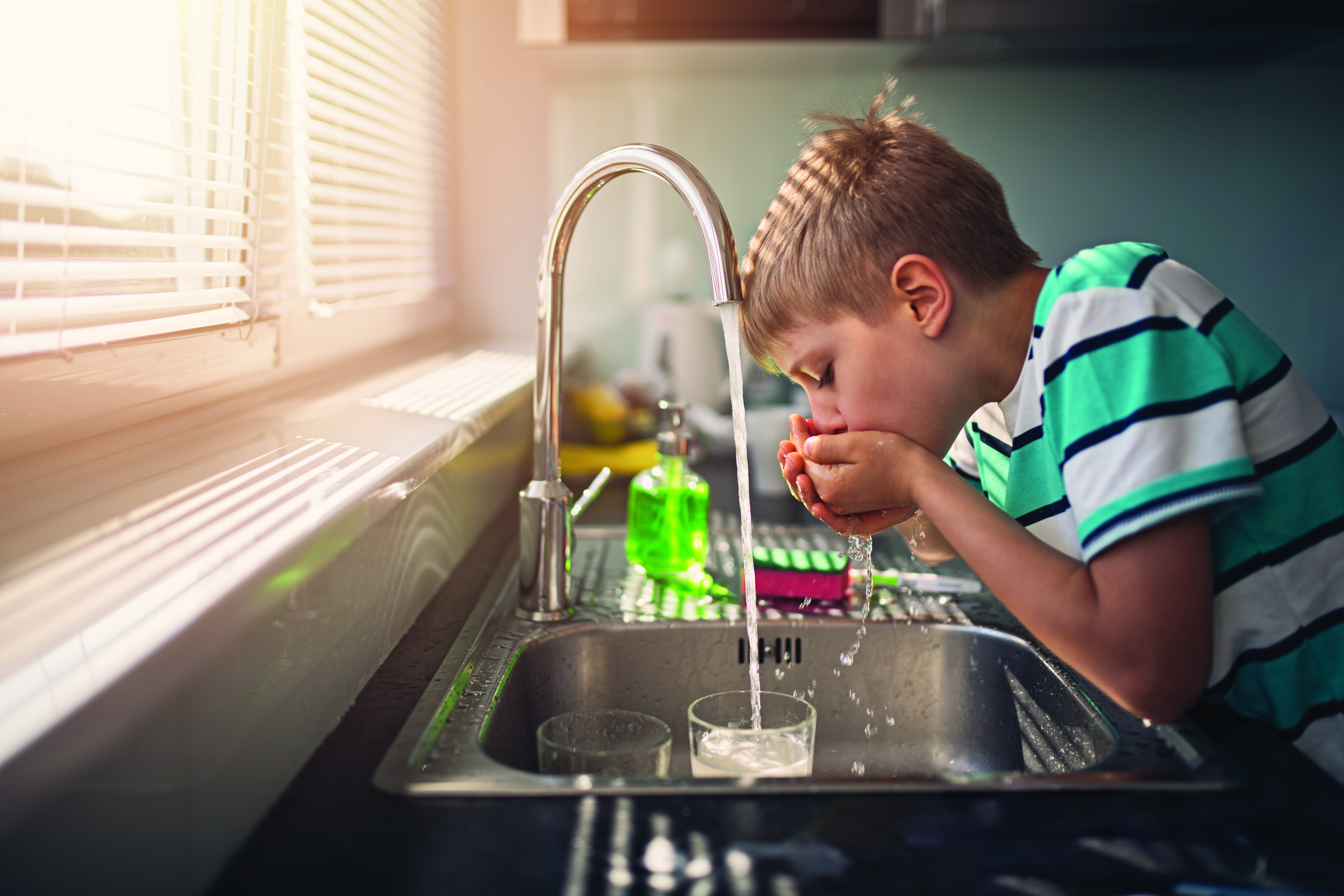 Little boy drinking tap water. Little boy aged 8 is drinking tap water in kitchen