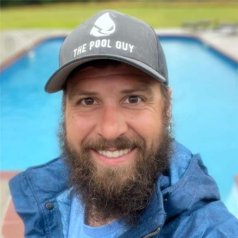 Tim Holt. A white man with a brown beard. Smiling in front of a pool. 