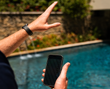 A mans hand holding a cell phone explaining somthing. 