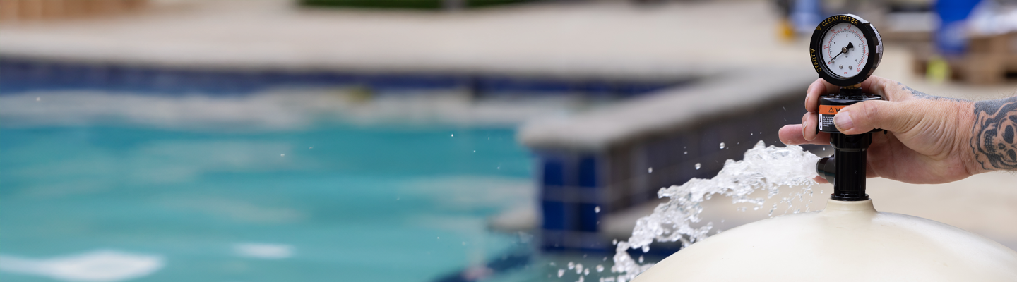 A pool is in the background. On the right side is a pool filter being safely depressurized.