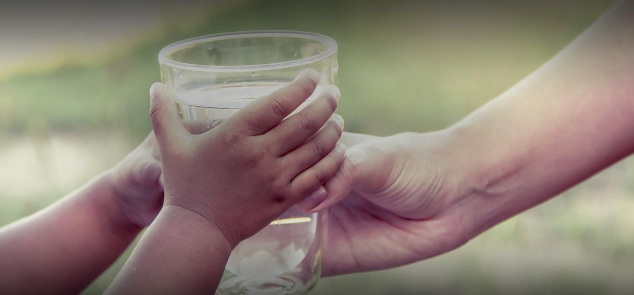 child-woman-hands-holding-water-glass-outdoor-green-grass-cropped-horizontal-1440x672-image-file