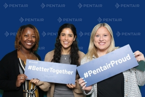 Three Pentair employees holding signs at a Golden Valley return to office event