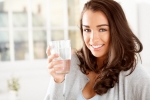 smiling-young-woman-in-grey-sweater-holding-water-glass-at-home-horizontal-5616x3744-image-file-148031785