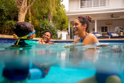 Two parents playing with sun in pool 