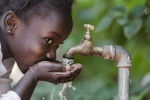 young-girl-drinking-water-from-outdoor-faucet-with-green-plants-in-background-horizontal-4552x3016-image-file-474251868