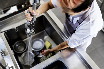 Top view of kitchen staff washing utensils at sink