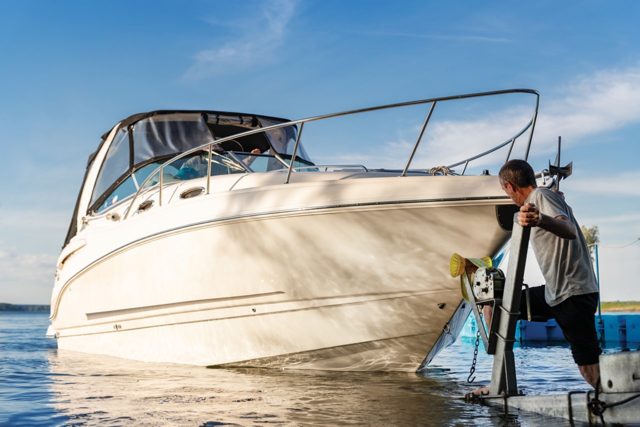 A man standing on a dock looking at his boat floating calmly in the water; Adobe Stock: 362897493