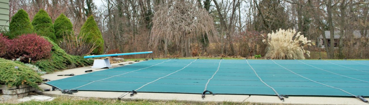 Aqua pool cover on inground pool with diving board and leaf changing 