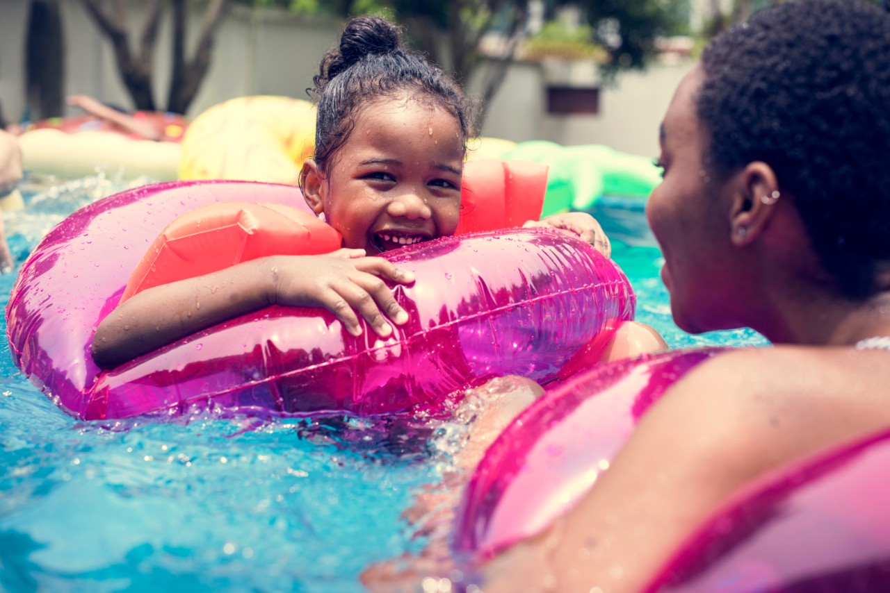 Closeup of mother and daughter enjoying the pool with inflatable tubes; african american; 