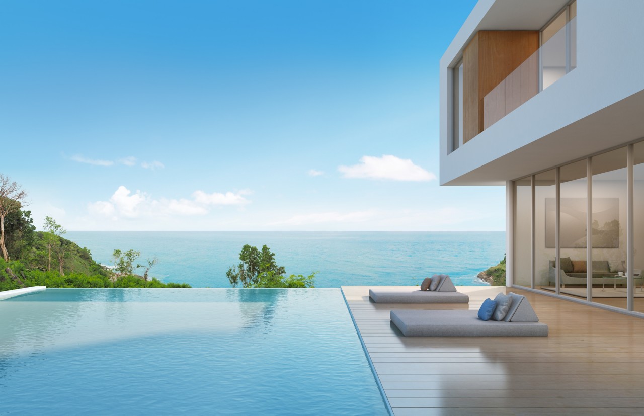 modern backyard infinity pool overlooking ocean with trees and inground beach chairs