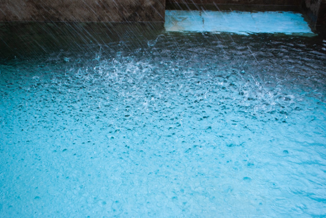 Water surface of the pool with splashes. Water drops falling on the pool. Raining over the pool. ; Shutterstock ID 1844210023; purchase_order: march pool images; job: 