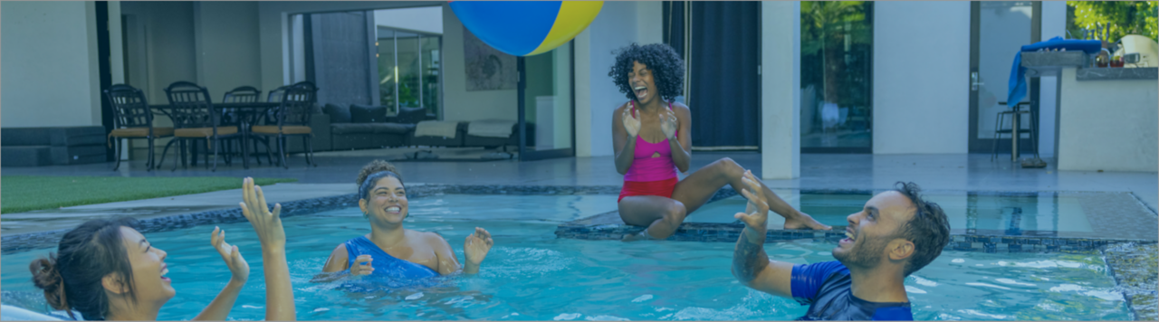 Three women and one man playing in pool with beach ball