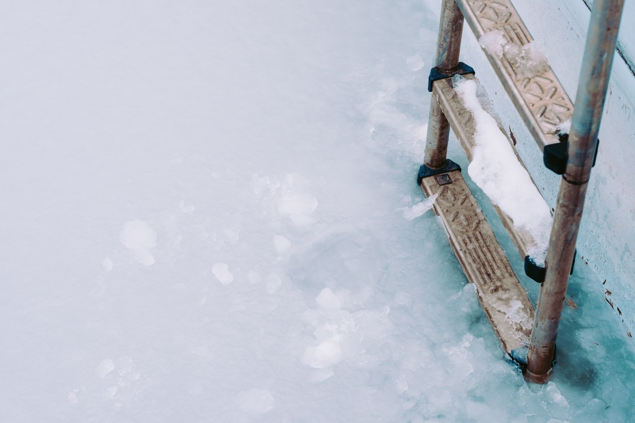 Interior of a pool frozen with a ladder covered in ice.