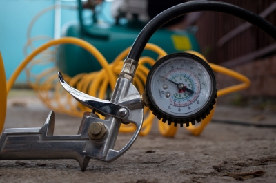 An air pressure gauge laying on the floor with black and yellow hoses