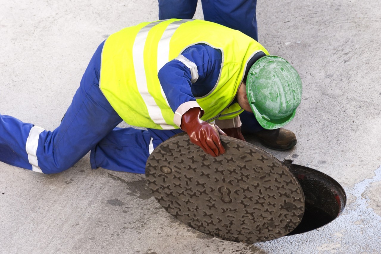 sewerage utility workers moves the manhole cover to cleaning the sewer line