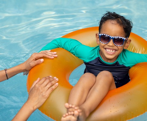 Little boy in pool in orange floatie