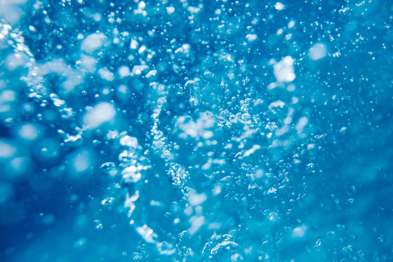 Air bubbles in clear blue water in pool underwater