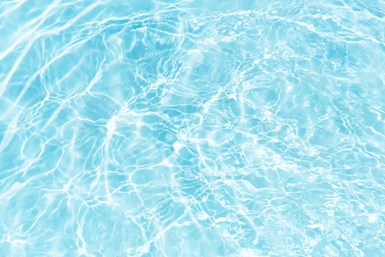 Bluewater waves on the surface ripples blurred. Defocus blurred transparent blue colored clear calm water surface texture with splash and bubbles. Water waves with shining pattern texture background.