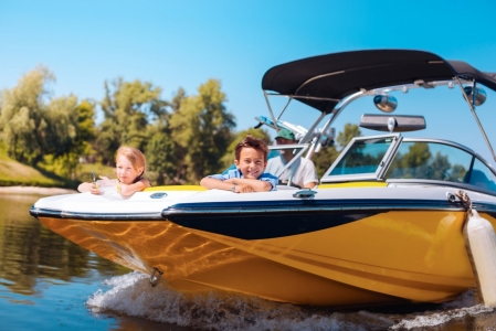 Breathtaking view. Joyful little siblings sitting on the bow of the boat and contemplating the view while smiling happily; Gettyimages: 993481846