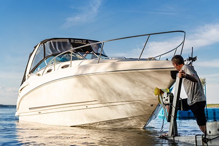 A man standing on a dock looking at his boat floating calmly in the water; Adobe Stock: 362897493