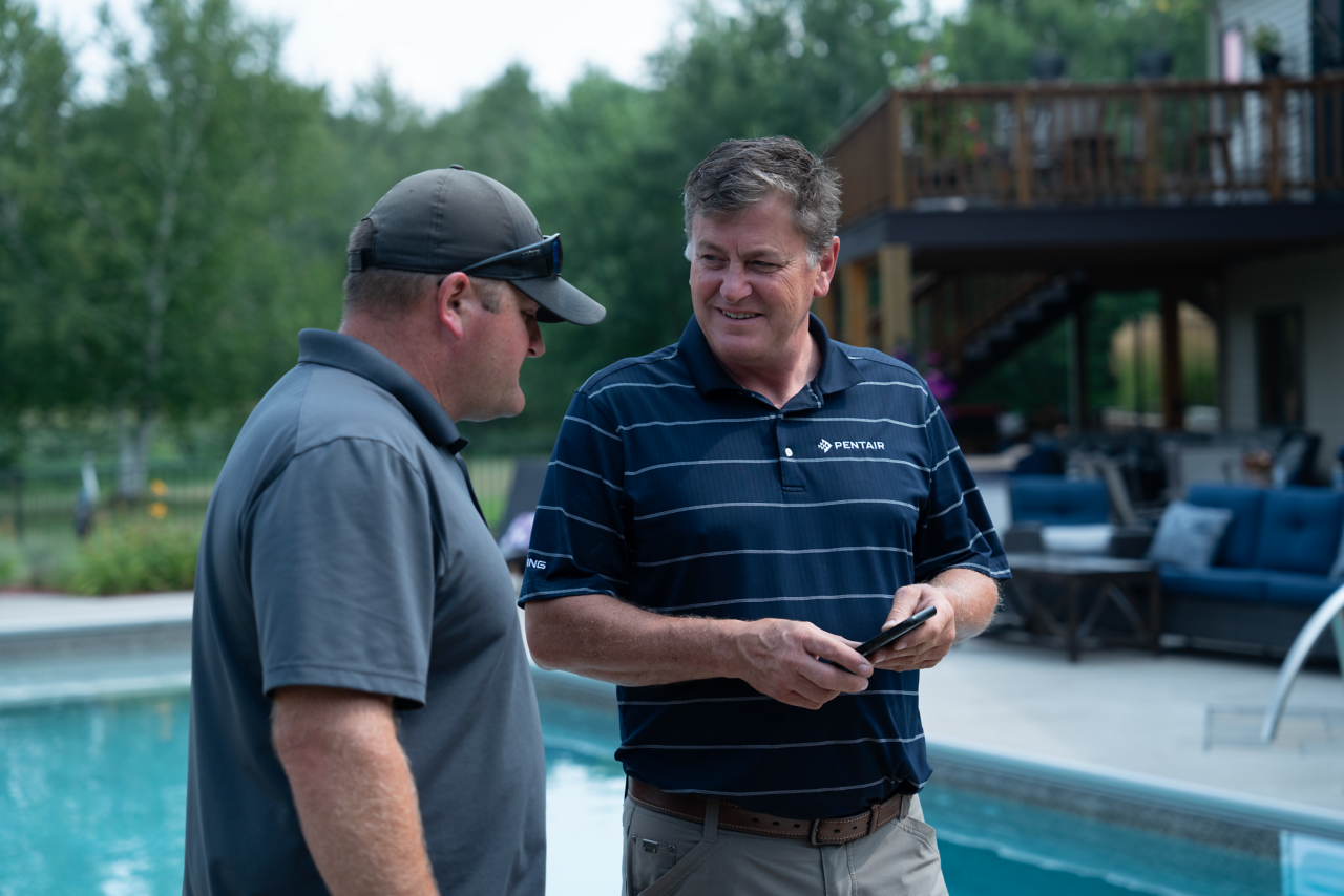 sales guy showing servicer phone from a wider angle from photoshoot in Ham Lake, MN
