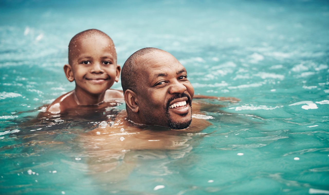 happy-man-and-boy-father-and-son-swimming-in-textured-blue-water-horizontal-5963x3529-image-917630596
