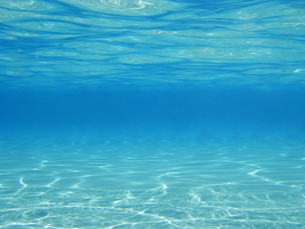sun reflecting in underwater swimming pool light dark blue