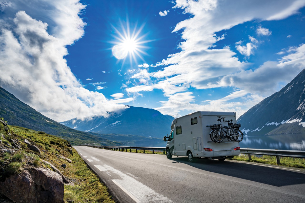 An RV driving through the mountains on a sunny day.