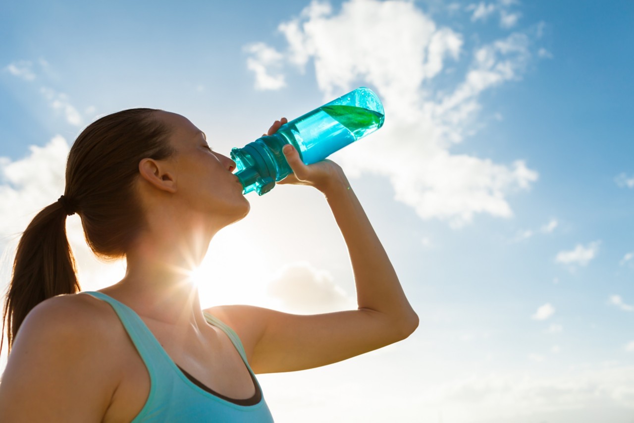 female-athlete-wearing-blue-shirt-drinking-water-from-bottle-with-blue-sky-on-sunny-day-horizontal-5616x3744-image-file-519369740