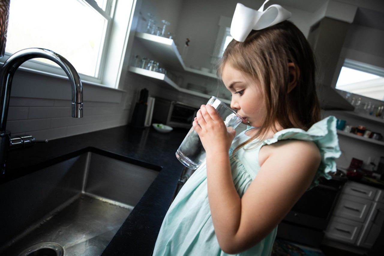 child drinking water glass in kitchen