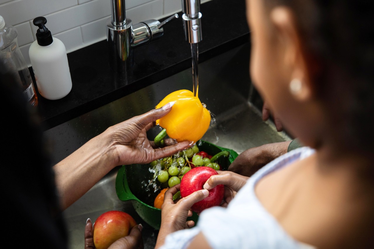 woman rinsing produce in sink