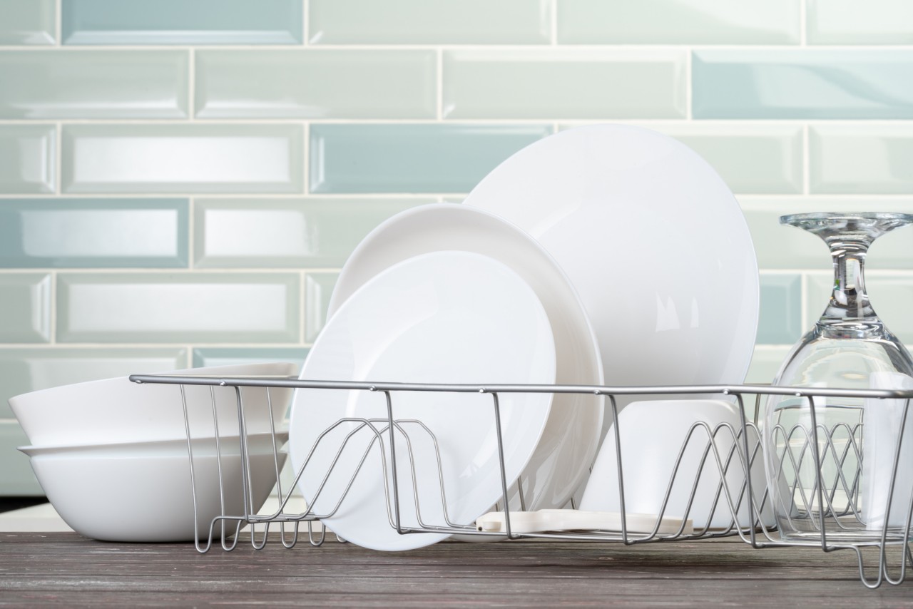 Dish rack with clean dry dishes on kitchen counter. Close up.