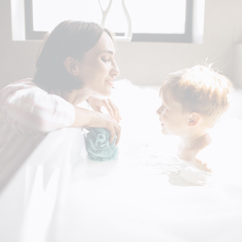 child taking bath while talking to mother