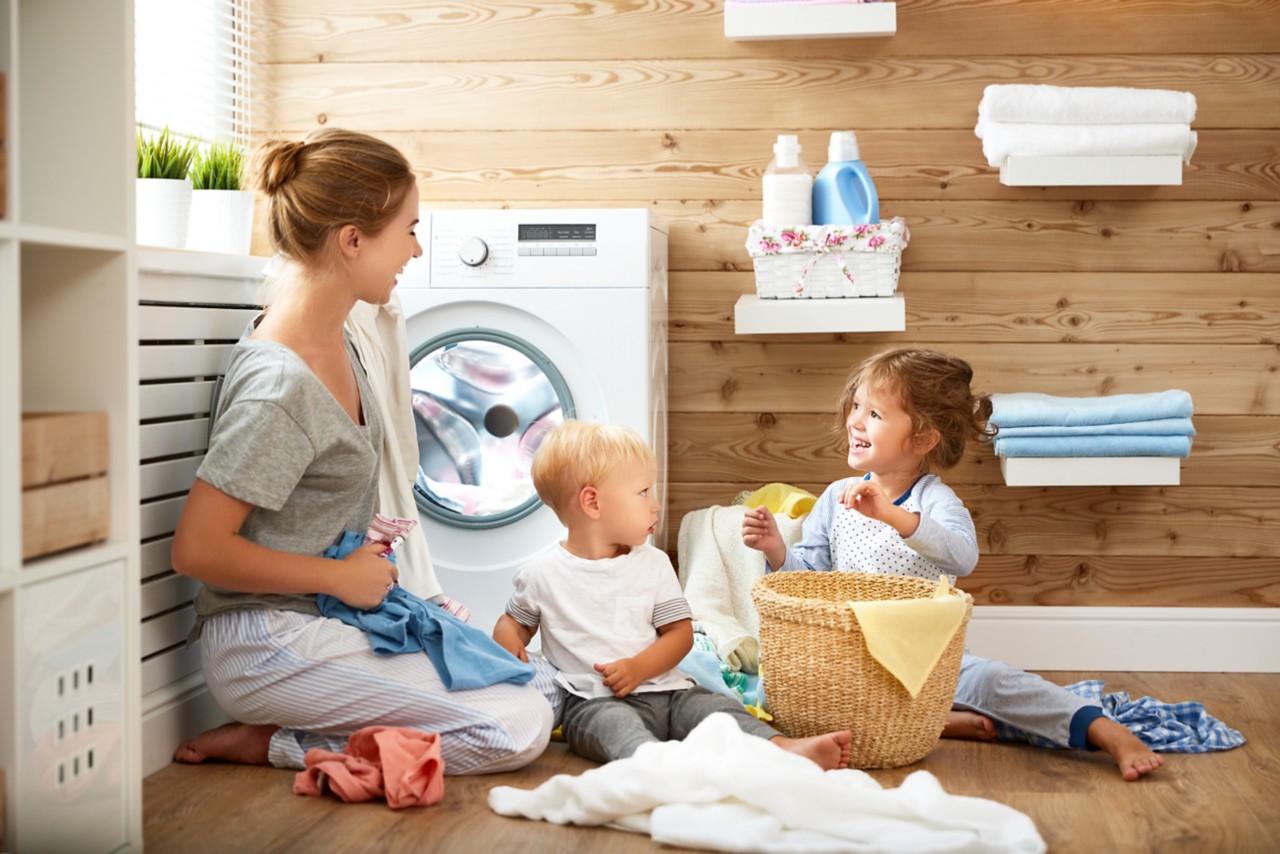 mother doing laundry on floor with children