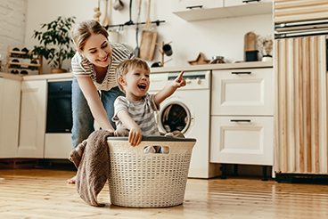 mother pushing son in laundry basket