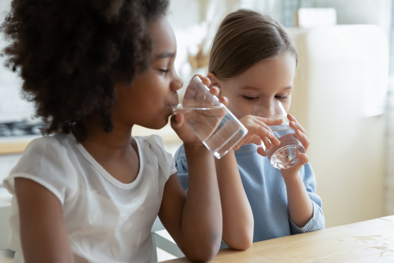 Two girls drink clean still natural water close up, hydration, water filration, water supply